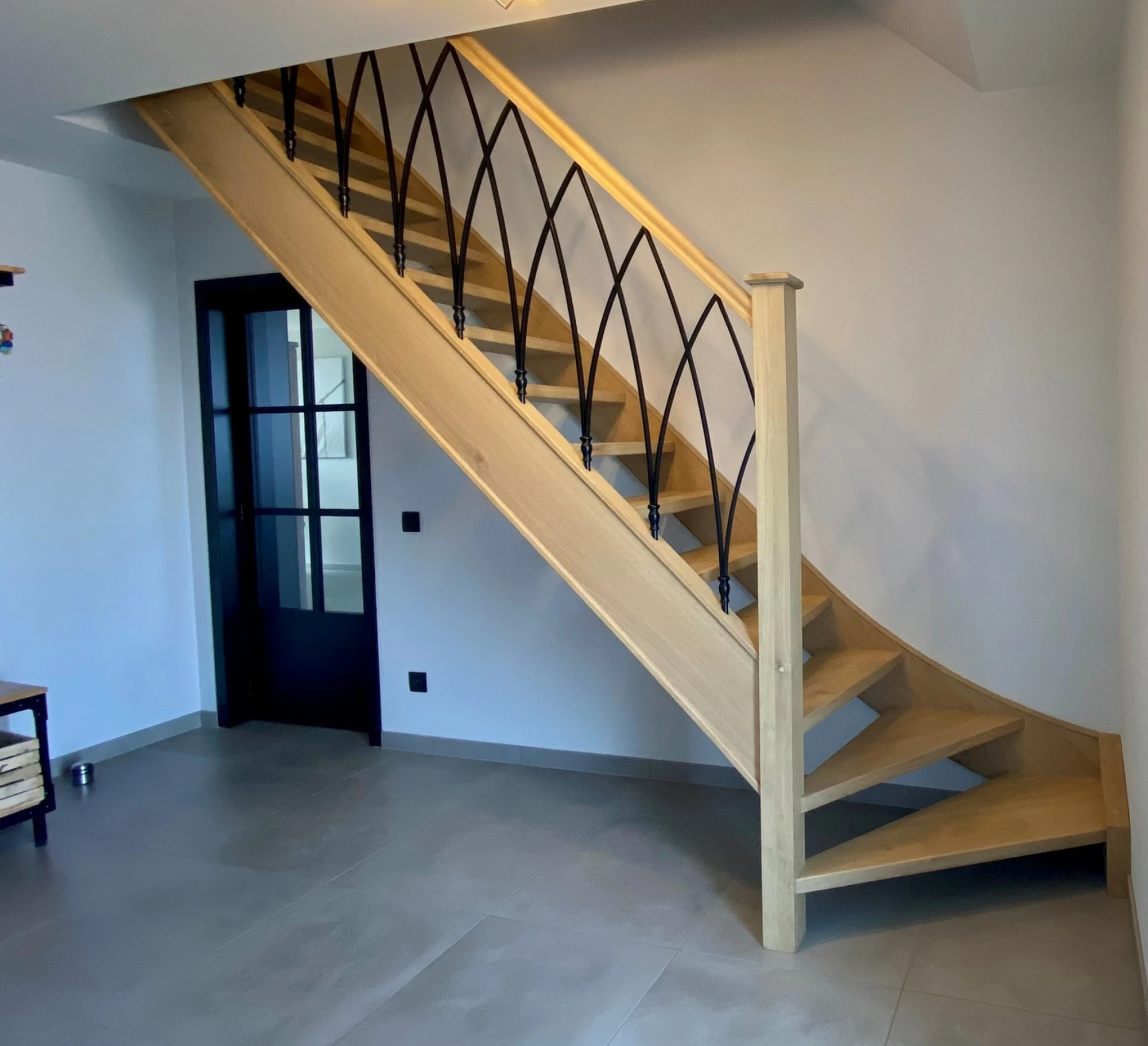 Eiken trap met smeedijzeren spijlen in boogmotief en een gedraaide trappaal