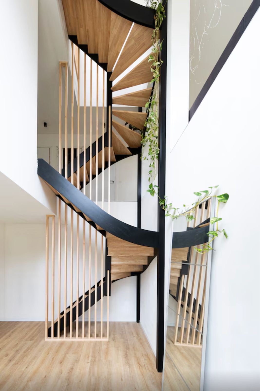 Open eiken trap met zwarte stalen leuning en houten spijlen